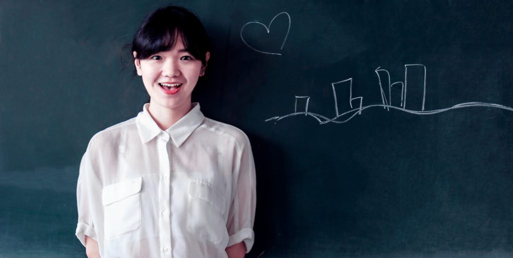 a girl standing next to the chalk board