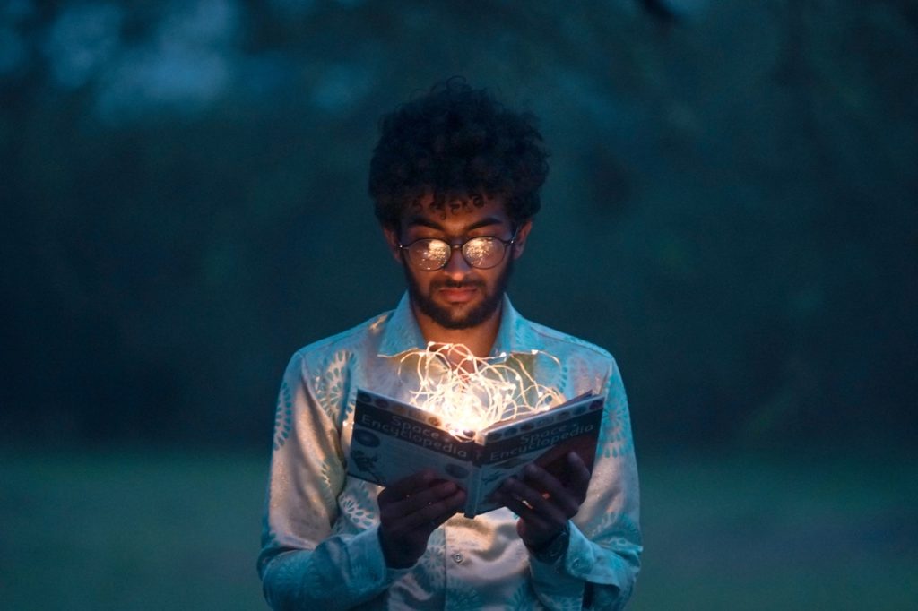 a man is holding a book with the string lights